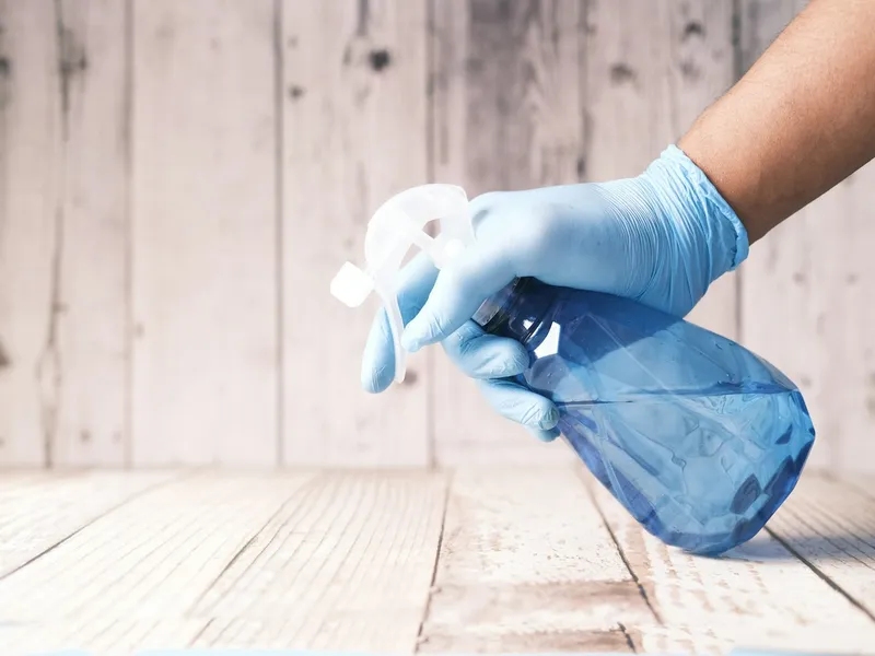 Close-up of a gloved hand holding a spray bottle for detail cleaning